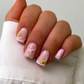 Hand with pink nail art featuring starfish and shell designs on a white background, Obroi