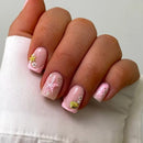 Hand with pink nail art featuring starfish and shell designs on a white background, Obroi