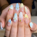 Nails with floral designs and gradient colors held by a hand, Obroi