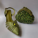 Green high-heeled shoe with embellishments and a matching green handbag on a light gray background, Obroi