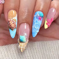 Close-up of a hand with colorful nail art featuring shells, flowers, and bubbles, Obroi