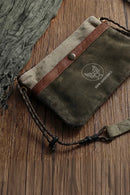 Waxed canvas pouch with brown leather strap on a wooden surface, Obroi