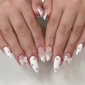 Close-up of hands with white nail polish featuring red polka dots and small decorative bows on a light background, Obroi