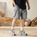 Person wearing gray shorts and sneakers in a room with wooden logs and vases.