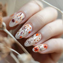 Nails with floral design held by a hand, Obroi