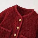 Close-up of a red textured garment with gold buttons on a light gray background, Obroi
