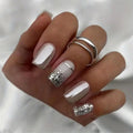 Hand with beige and silver glittery nail design on a white background, Obroi