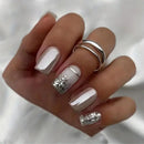 Hand with beige and silver glittery nail design on a white background, Obroi