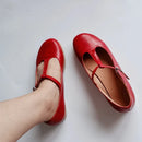 Red leather shoes worn by a person on a light gray background, Obroi