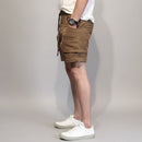 Person wearing brown shorts and white sneakers against a white background, Obroi