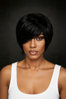A woman wearing a short, layered black wig with side-swept bangs, shown from the chest up against a dark gray studio background, Obroi
