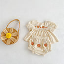 Baby romper with floral design and straw bag with flower on a white background, Obroi