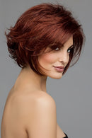 Woman with styled red hair against a gray background, Obroi