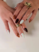 Close-up of hands with nail art and gold rings on a light background, Obroi