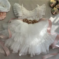 White children's dress with floral belt and pink ribbons on a light background, Obroi