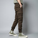 Person wearing brown cargo pants and green high-top sneakers against a white wall, Obroi