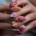 Close-up of a hand with colorful floral nail art on a blurred background, Obroi