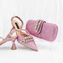 Pink glittery high-heeled shoes with embellishments and a matching pink clutch on a white background, Obroi