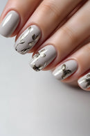 Nails with white polish and gold butterfly designs on a neutral background, Obroi