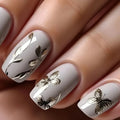 Nails with white polish and gold butterfly designs on a neutral background, Obroi
