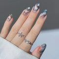 Hand withShell-inspired nail art and silver rings on a neutral background,Obroi