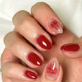 Close-up of a hand with red nail polish and decorative bow designs on a white background, Obroi