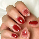 Close-up of a hand with red nail polish and decorative bow designs on a white background, Obroi