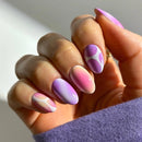 Hand with pink and purple gradient nails on a neutral background