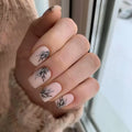 Nails with black leaf designs on a neutral background