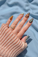 Close-up of a hand with artistic nail designs, wearing a textured sleeve and ring, Obroi