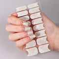 Hand holding a sheet of clear nail extensions against a neutral background, Obroi