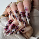 Close-up of a hand with long, intricately designed nails featuring pink, black, and gold patterns, Obroi