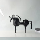 Black horse sculpture on a white surface with a white wall background, Obroi