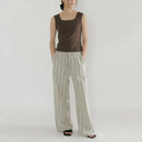 A woman modeling a sleeveless brown top and wide-leg striped pants in a studio setting with a white background, Obroi