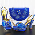Blue high-heeled shoes and matching handbag with decorative elements on a white background, Obroi