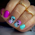 Nail art with palm tree designs and colorful gradient on a hand wearing gold rings, Obroi