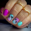 Nail art with palm tree designs and colorful gradient on a hand wearing gold rings, Obroi