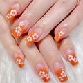 Nails with orange and pink gradient design featuring white flowers on a white , Obroi