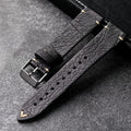 Black leather watch strap with gold accents on a dark surface, Obroi