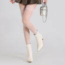 Obroi Person wearing beige polka dot tights and white ankle boots on a light gray background