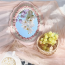 Decorative mirror with floral design on a soft pink fabric background