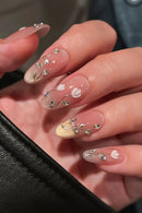 Close-up of hands with decorative nail art featuring small flowers and beads, Obroi