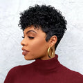 Woman with short, curly black hair wearing a maroon turtleneck and gold hoop earrings against a light gray background, Obroi