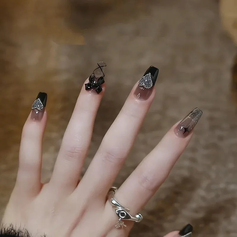 Obroi Close-up of a hand with black and silver nail art on a blurred background