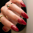 Close-up of a hand with red nail polish and gold rings on a blurred background ,Obroi
