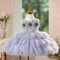 Children's gray dress with floral embellishments on a mannequin against a blurred indoor background, Obroi