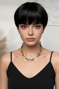 Woman wearing a gold chain necklace against a neutral background, Obroi