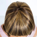 Close-up of a person with brown hair styled in a bun against a white background, Obroi