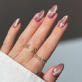 Hand with pink nail polish and floral designs, wearing multiple rings on a neutral background, Obroi