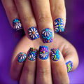Colorful floral nail art on a hand against a purple background, Obroi